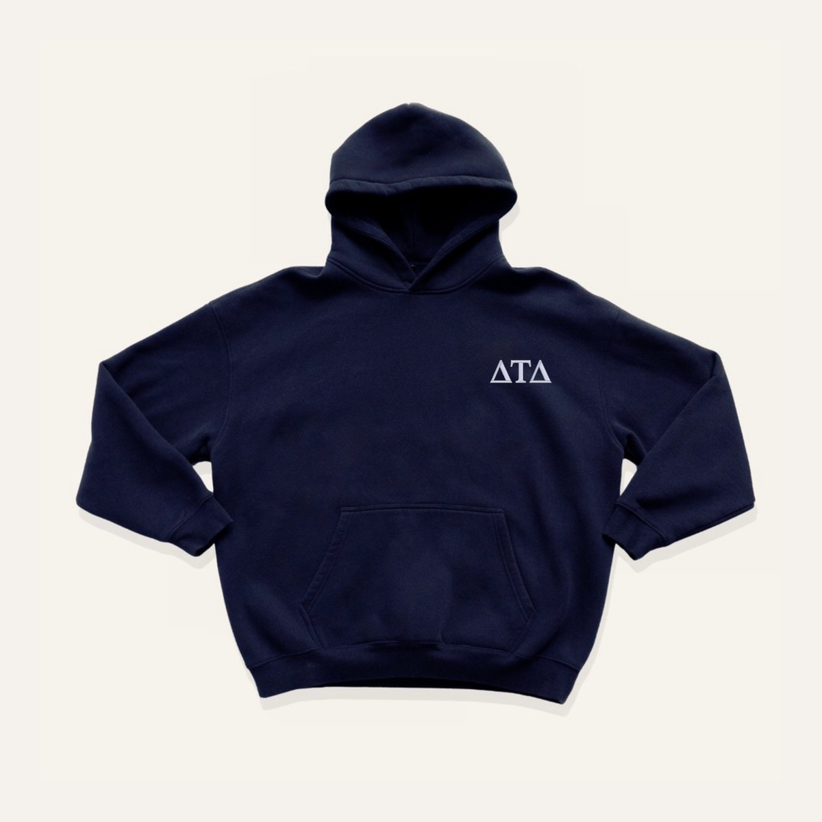 Navy blue hoodie on a cream background with 'Delta Tau Delta' greek letters in white on the right side chest.